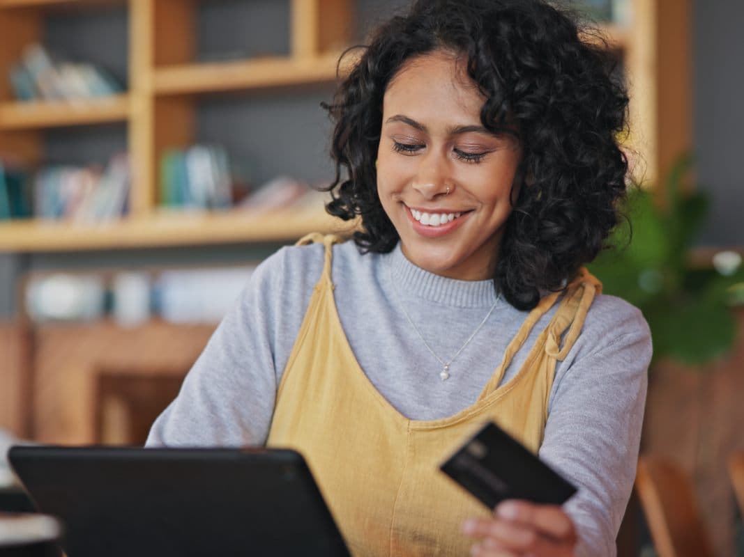 picture of a woman with credit card on hand, entering card details into website on her laptop.
